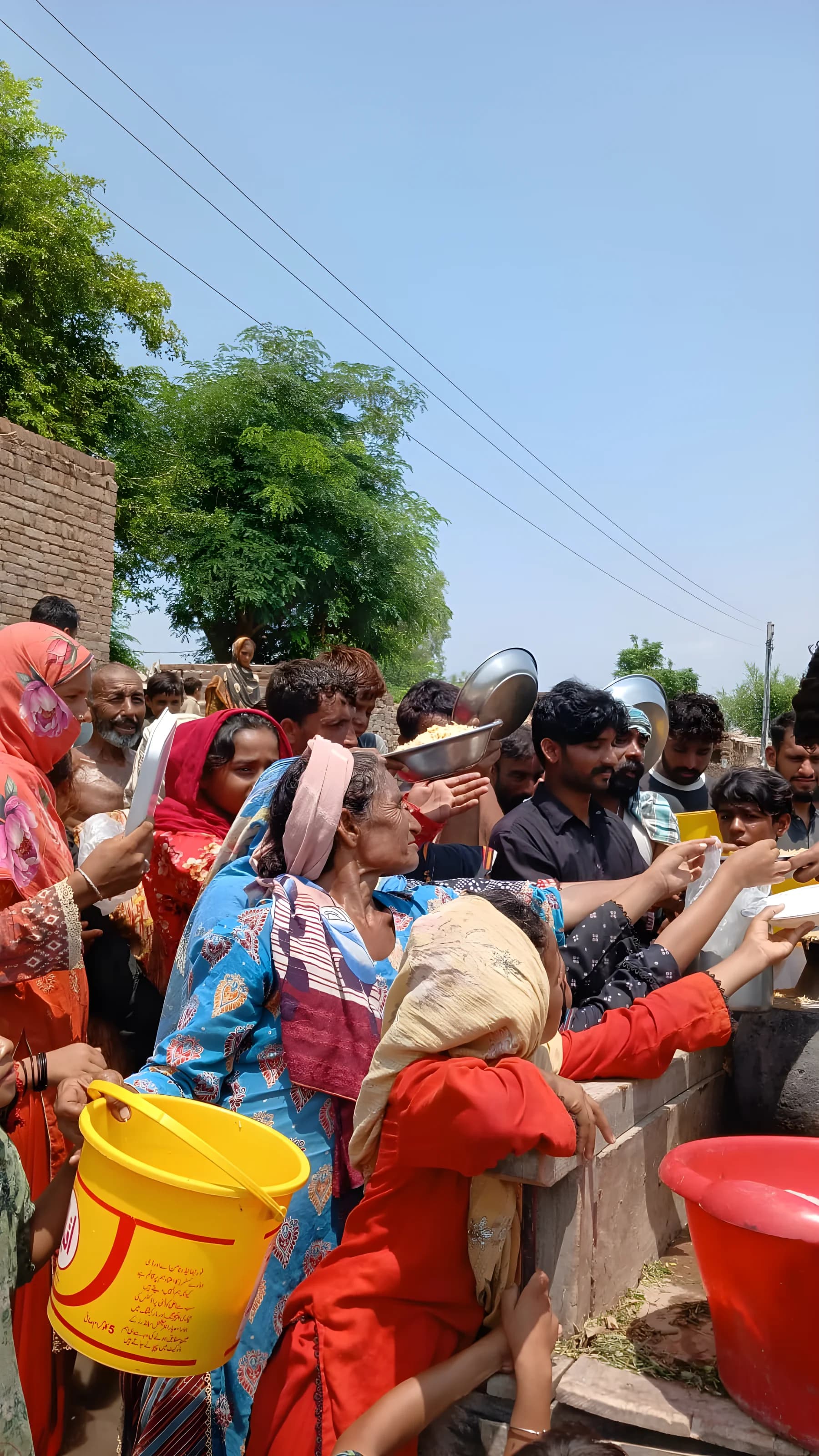 Utdeling av mat til en kø av mennesker i et flomrammet område i Pakistan